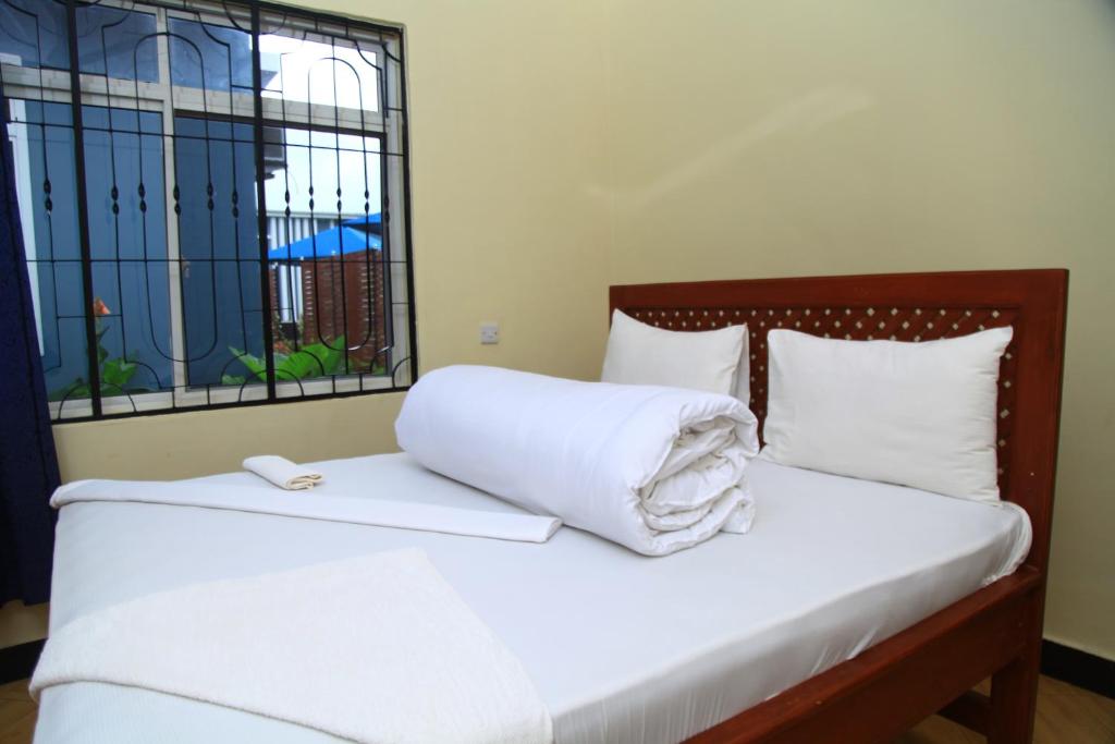 a bed with white sheets and pillows and a window at Johnsons Villas in Zame