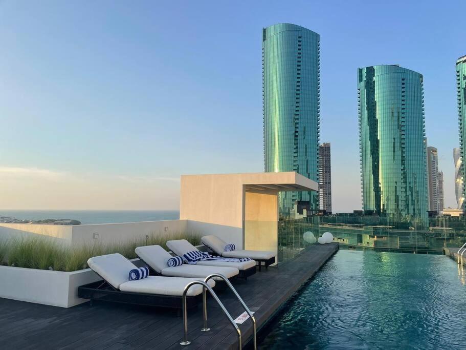 a pool with lounge chairs on the roof of a building at Cloud9 Waterfront Luxury Condo in Manama