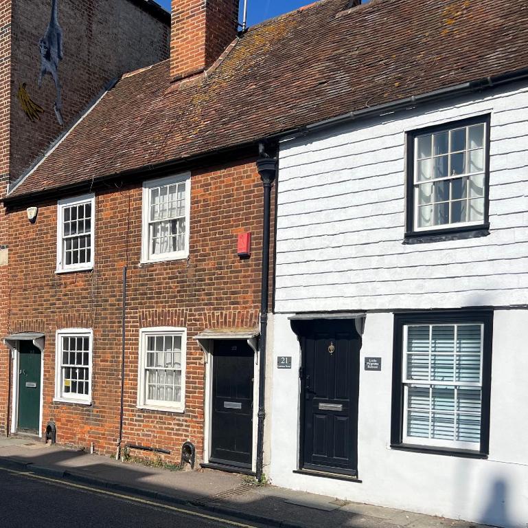 ein Backsteingebäude mit schwarzen Türen auf einer Straße in der Unterkunft Little Pilgrims Retreat in St Dunstans, Canterbury in Kent