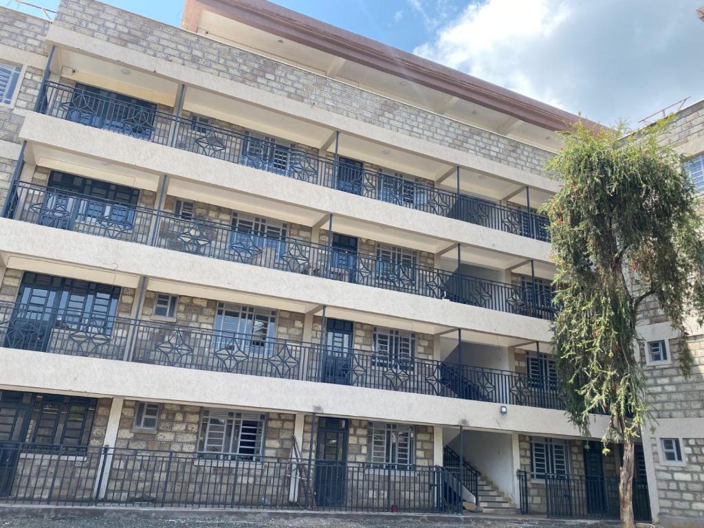 ein Apartmenthaus mit Balkon und einem Baum in der Unterkunft Amalya suites by TJ3 in Eldoret