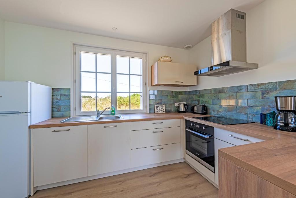 a kitchen with white cabinets and a window at Beach House 1km de la plage in Audierne