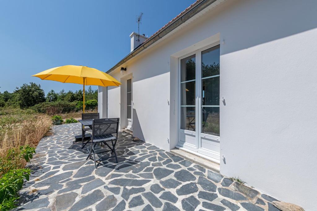 a patio with a yellow umbrella and a table and chairs at Beach House 1km de la plage in Audierne