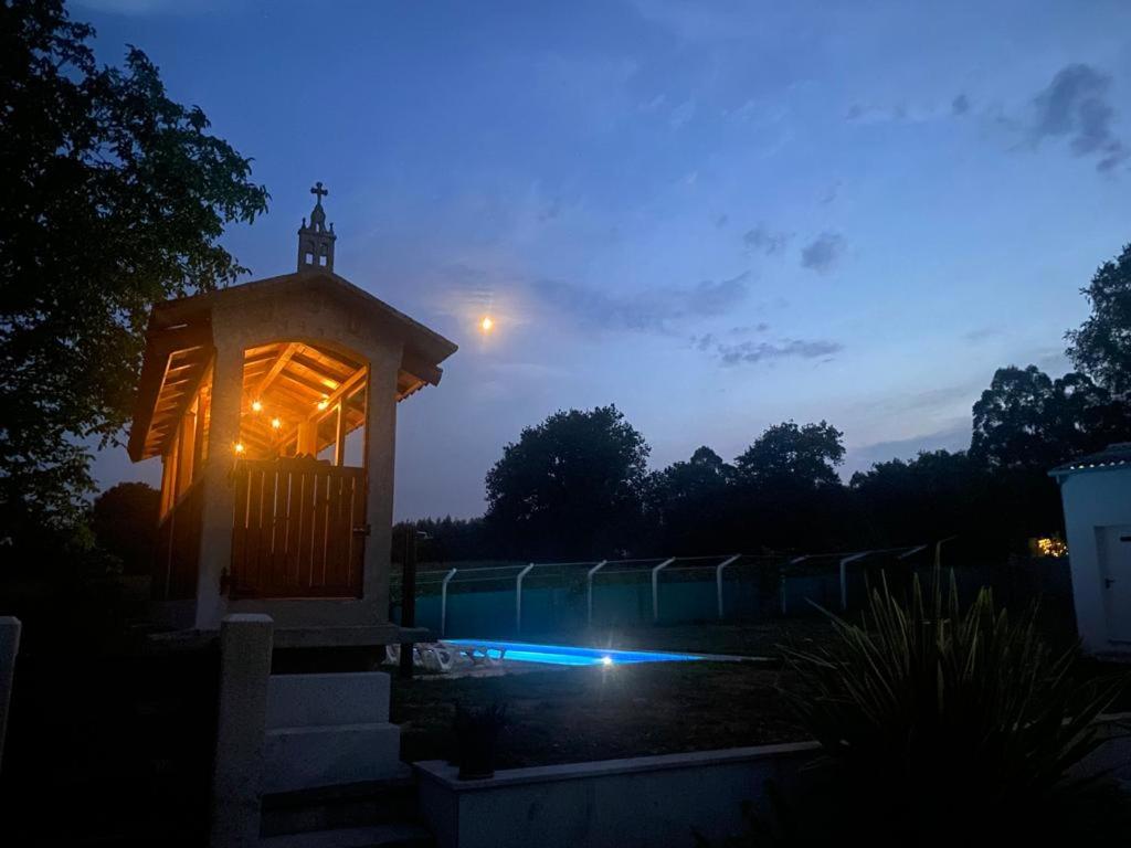 un cenador con luces en un patio por la noche en Casa Os Lindeiros ! Casa con PISCINA en Arzúa, en Arzúa