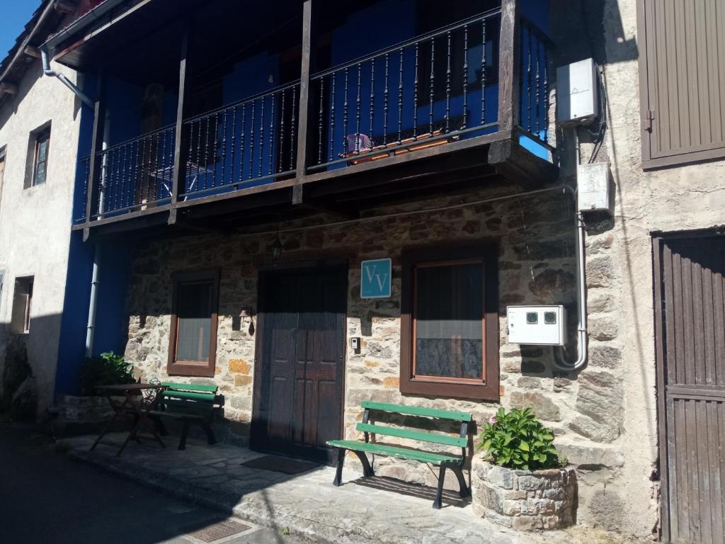 eine grüne Bank vor einem Gebäude mit einem Balkon in der Unterkunft Casa típica asturiana en Ribota in Celleruelo