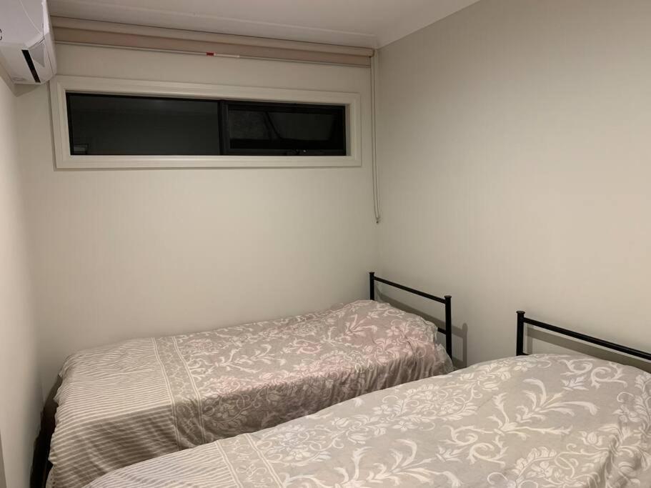 2 Betten in einem kleinen Zimmer mit Fenster in der Unterkunft 2 B/R, 2 Bath near public transport & Monash Univ. in Mulgrave