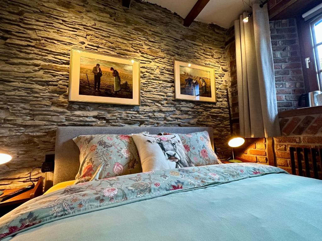 een slaapkamer met een bed en een stenen muur bij La Remise - Les Chambres in Neufchâteau