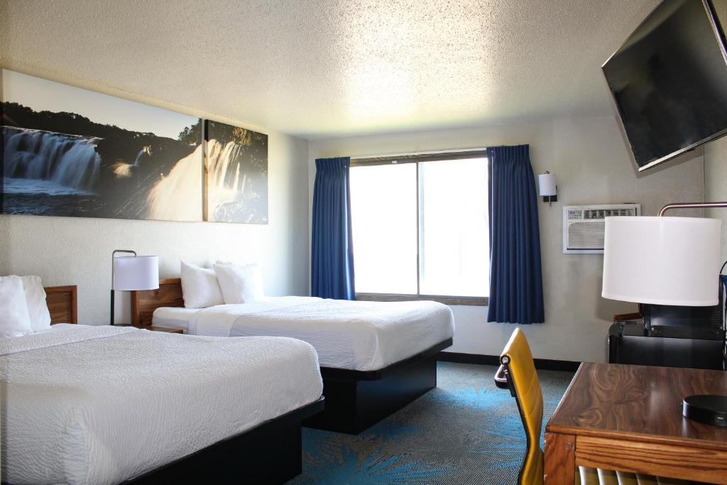 a hotel room with two beds and a window at Days Inn by Wyndham Sioux Falls in Sioux Falls