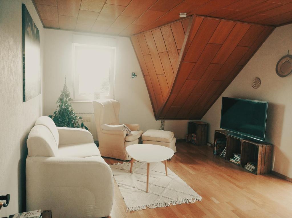 Il comprend un salon doté d'un mobilier blanc et d'une télévision. dans l'établissement Urlaub nähe Badesee und Strand, à Berumbur