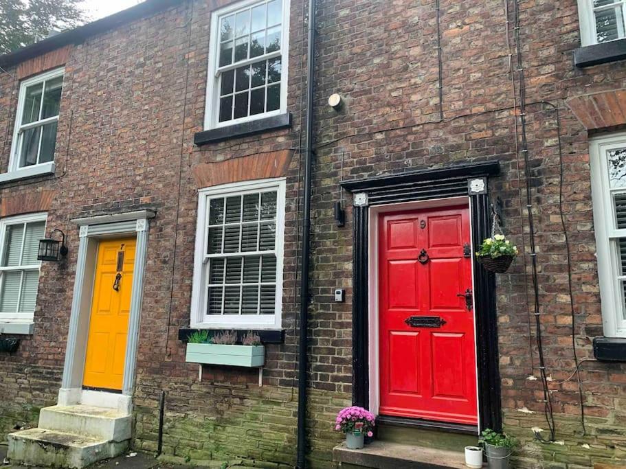 ein Backsteingebäude mit zwei roten Türen und Fenstern in der Unterkunft Cosy Cottage (Free parking) in Macclesfield