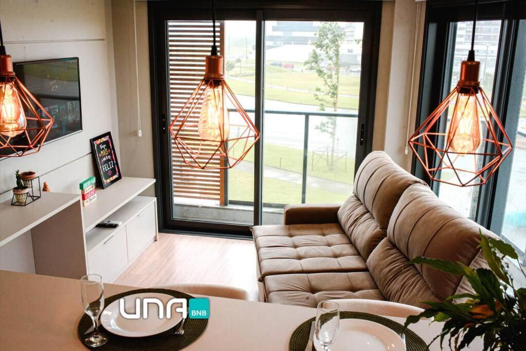 ein Wohnzimmer mit einem Sofa und einem Tisch in der Unterkunft Apartamento no Parque Una com vista espetacular in Pelotas