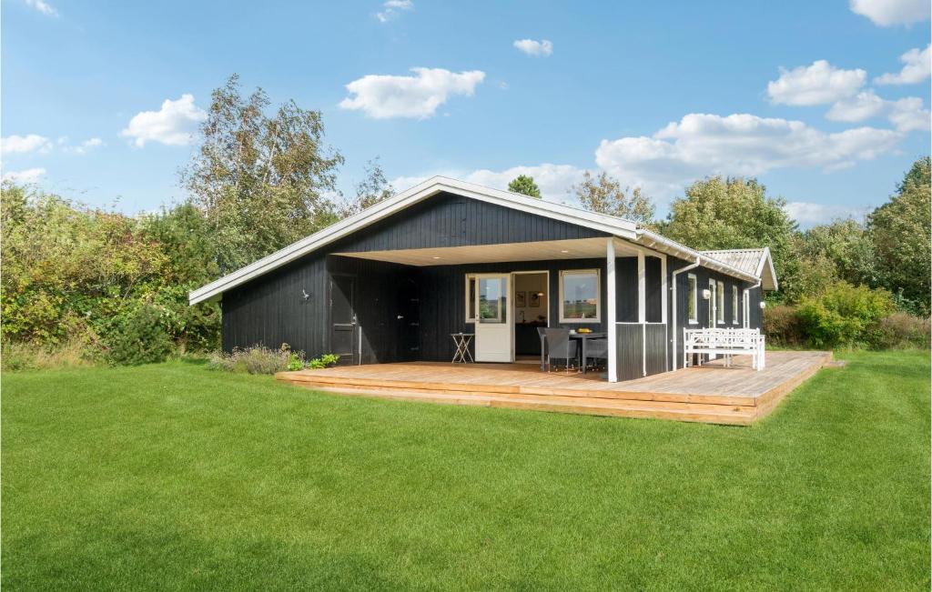 une maison noire avec une terrasse en bois dans une cour dans l'établissement Cozy Home In Sams With Kitchen, à Nordby