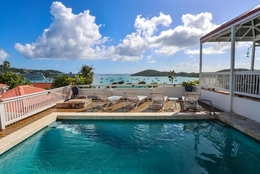 a swimming pool with chairs and the ocean in the background at At Home in the Tropics in Charlotte Amalie