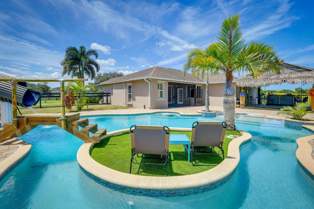 a swimming pool with two chairs in front of a house at Fort Pierce Escape Beach-Entry Pool, Waterslide! in Fort Pierce