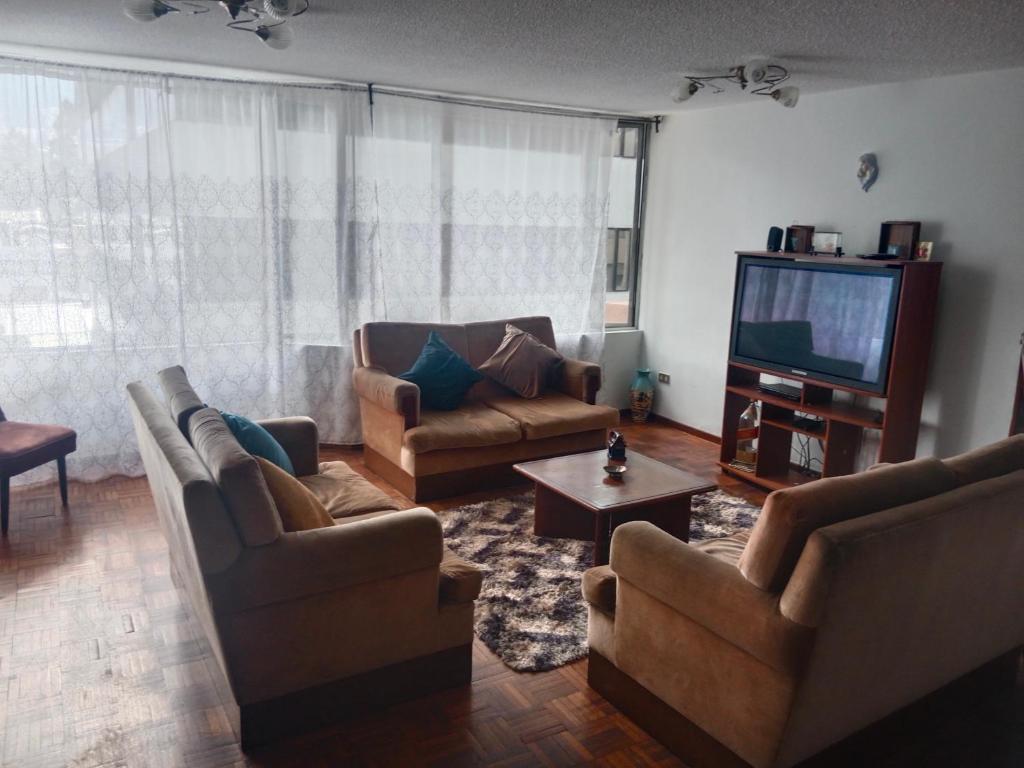 ein Wohnzimmer mit Sofas und einem Flachbild-TV in der Unterkunft Departamento 3 habitaciones in Quito