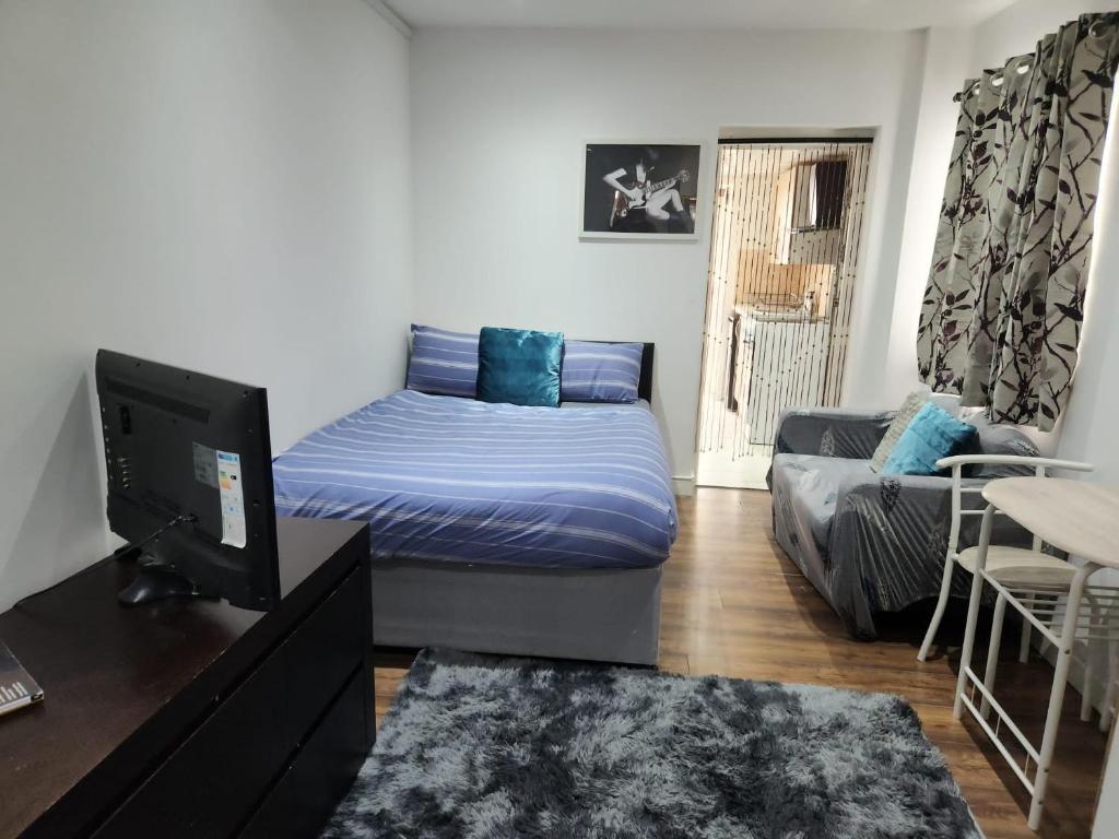 sala de estar con cama y sofá en Studio Apartment at Chadwell Heath en Romford