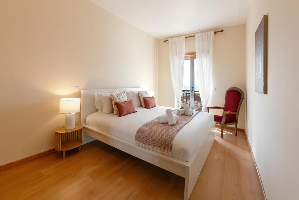 a bedroom with a large white bed and a window at Sunset Retreat in Nazaré