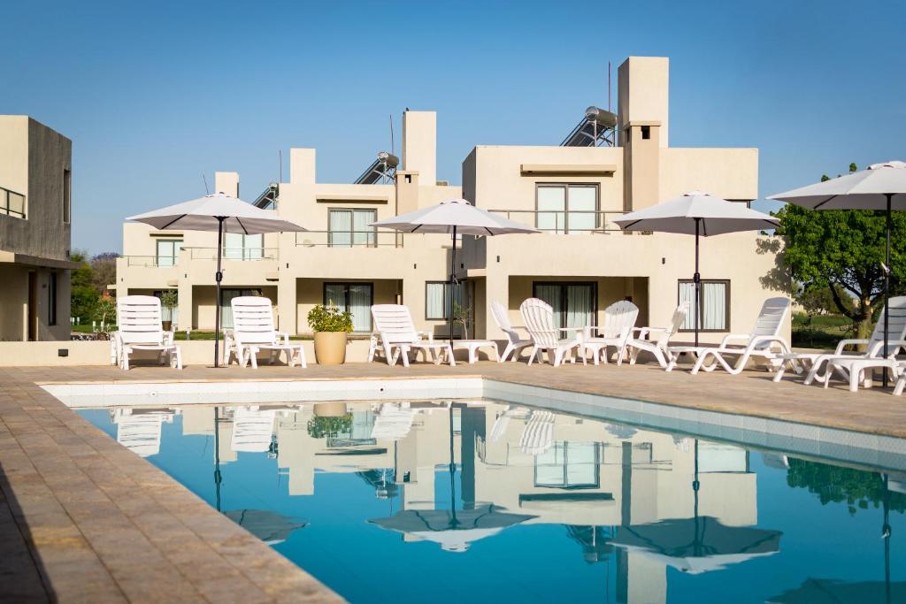 un complejo con piscina, sillas y sombrillas en Casa Adela - Cabañas Resort en La Rioja