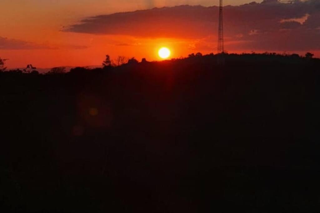 una puesta de sol sobre un campo con el sol en el cielo en Chalé no alto com bela vista., en Mulungu
