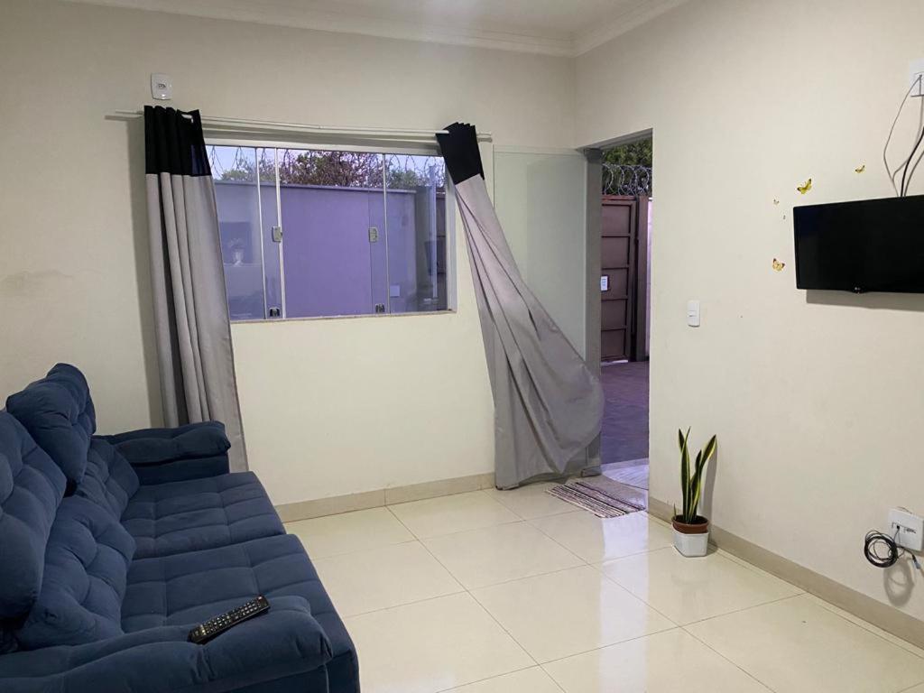 a living room with a blue couch and a window at Apartamento terreo com quintal individual in Patos de Minas