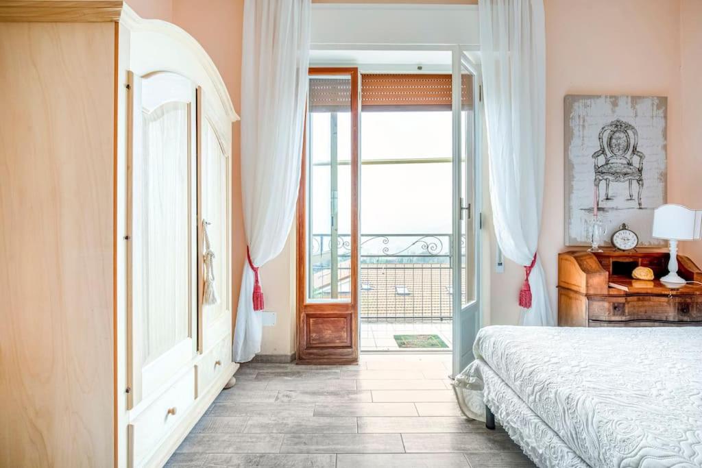 1 dormitorio con 1 cama y puerta a un balcón en Annali Casa vacanze - Shabby style nella natura, en La Spezia