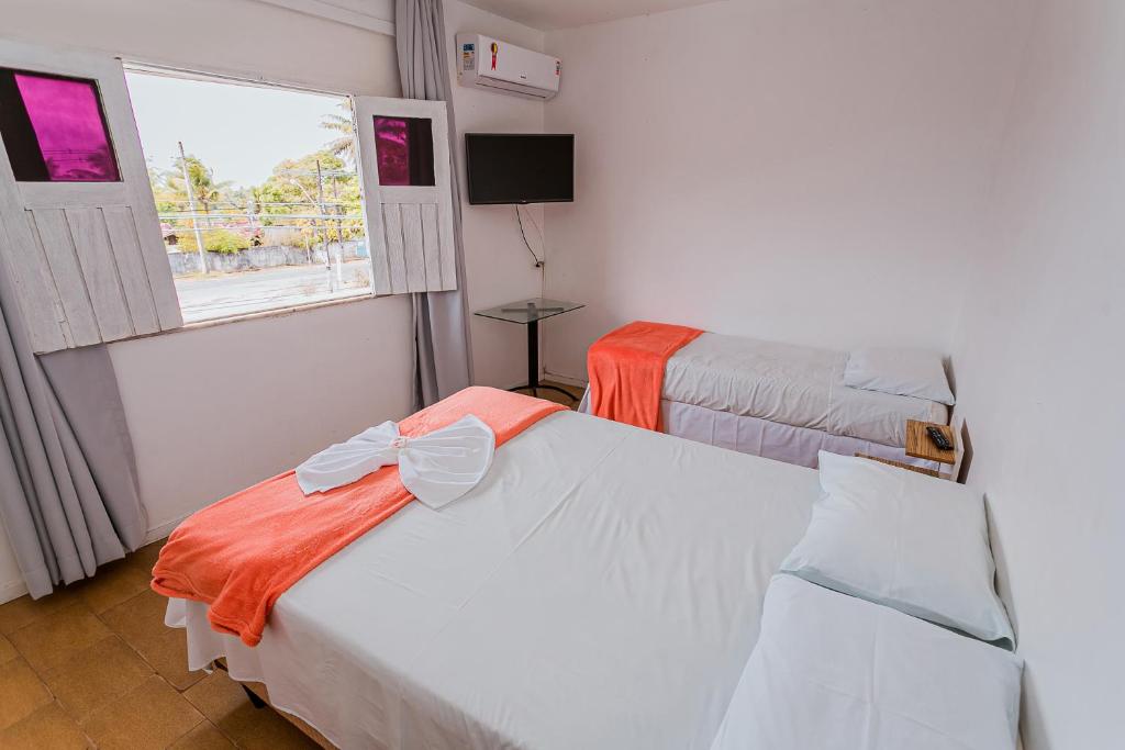 Duas camas num quarto com uma janela em Pousada Paulett's em Ilhéus