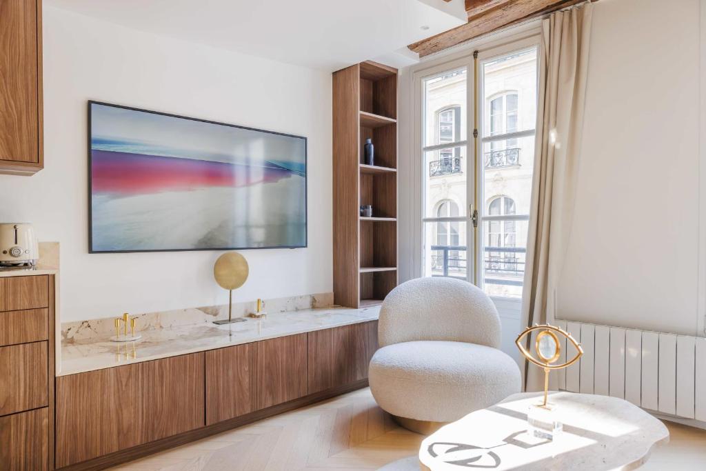 - un salon avec une télévision et une chaise dans l&#39;établissement Stunning Oasis near Louvre and Saint-Honoré - 1 Bedroom, à Paris