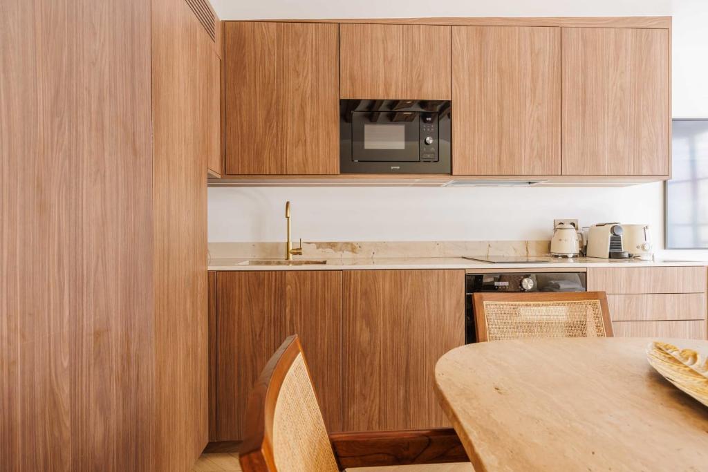 une cuisine avec des placards en bois et une table avec un four micro-ondes dans l&#39;établissement Stunning Oasis near Louvre and Saint-Honoré - 1 Bedroom, à Paris