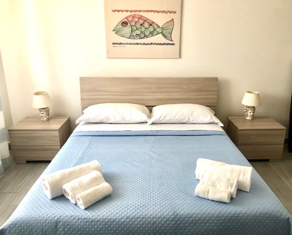 een slaapkamer met een blauw bed met 2 handdoeken erop bij Casa Gio - Appartamenti Vacanze in Villaggio Azzurro