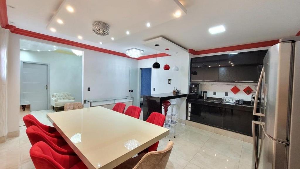 a kitchen with a white table and red chairs at Espetacular apartamento no centro in Palmas