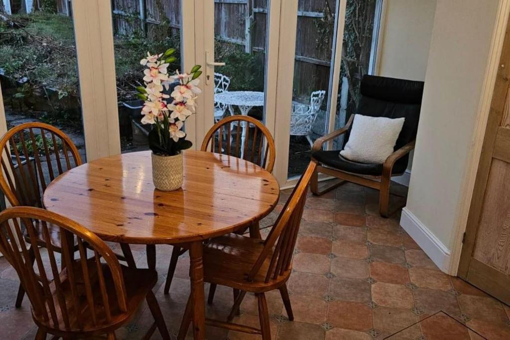een houten tafel met stoelen en een vaas met bloemen bij Beautiful Spacious 5 Bed House in Fornham Saint Martin