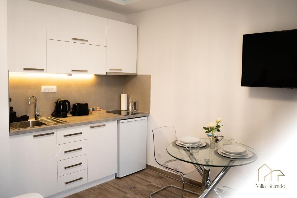 a kitchen with white cabinets and a glass table at Belrado Apartments in Belgrade