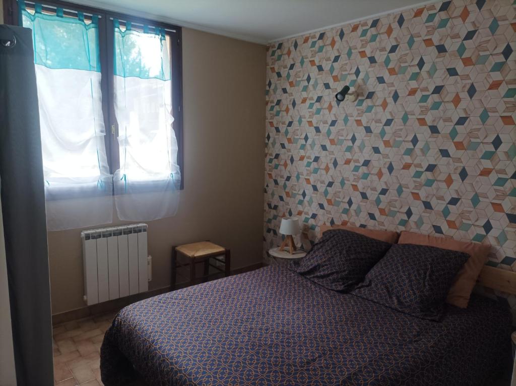 a bedroom with a bed and a wall covered in tiles at patrice et chrstel Appartement indépendant in Les Malossannes