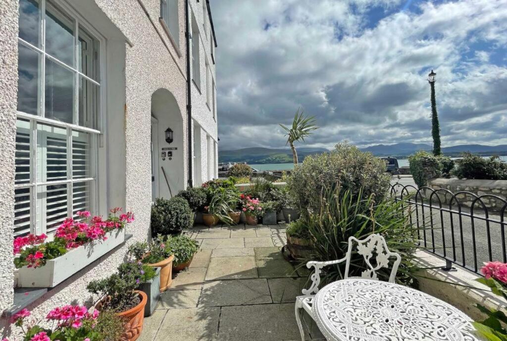 a white bench sitting on a balcony with flowers at Awel y Mor in Beaumaris