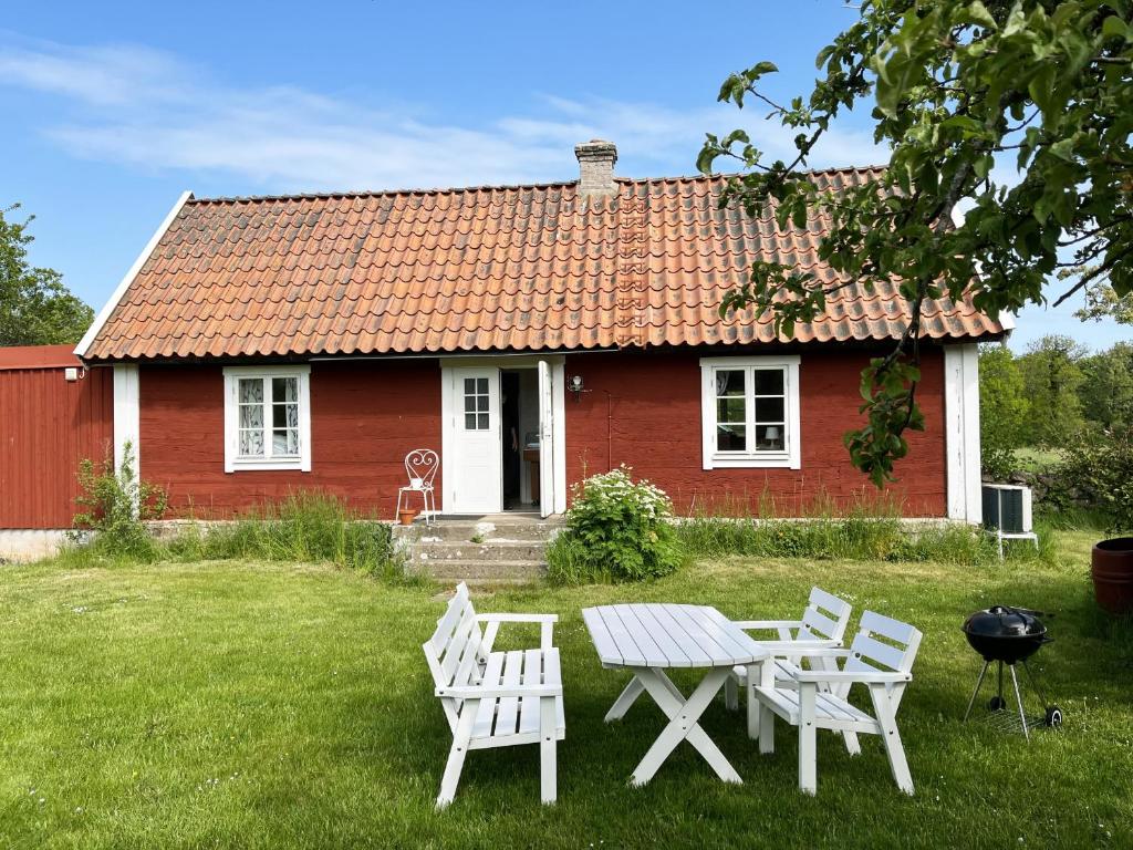 una casa roja con una mesa y sillas frente a ella en Nice holiday home on Oland with grazing sheep in the surroundings en Borgholm