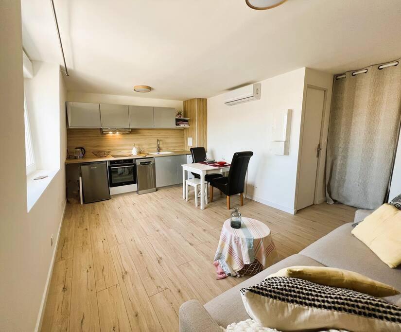 eine Küche und ein Wohnzimmer mit einem Sofa und einem Tisch in der Unterkunft Studio " Le Nid Perché" in Mers-les-Bains