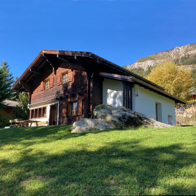 a log house with a large rock in front of it at Chalet près des bisses in Savièse