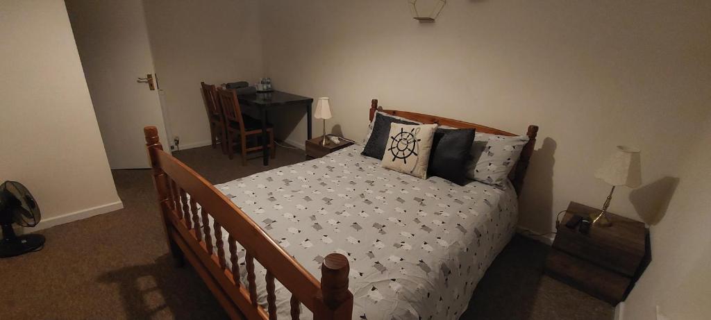 a bedroom with a wooden bed with pillows and a desk at The Helm in Pembrokeshire