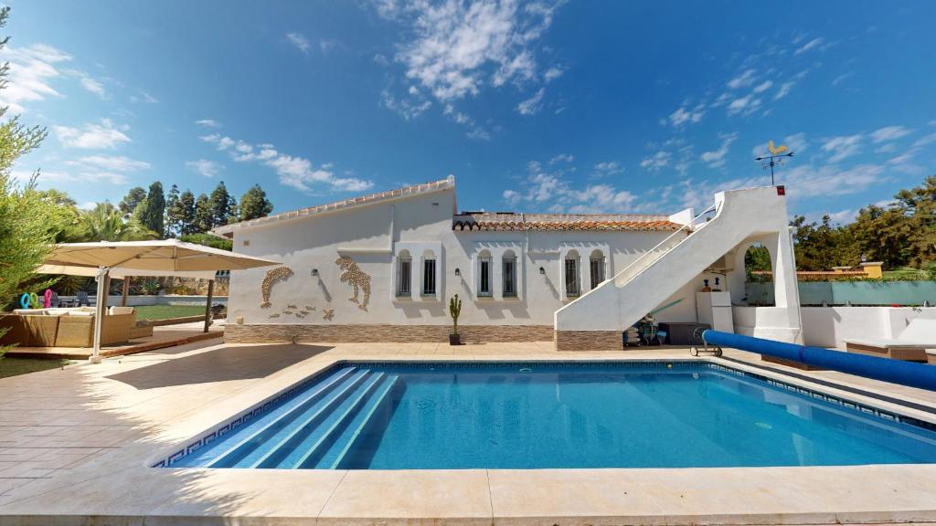 a swimming pool with a slide in front of a house at El Chaparral - Renovated Villa in La Cala in Mijas Costa