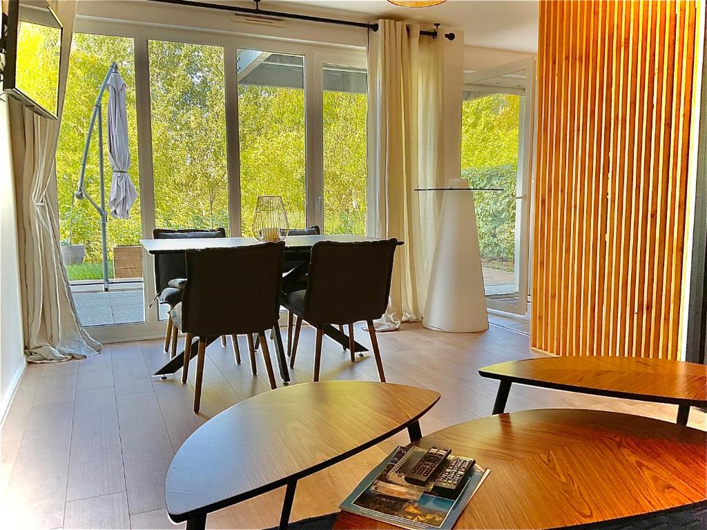 sala de estar con mesa, sillas y ventanas en Le Safran, en Obernai