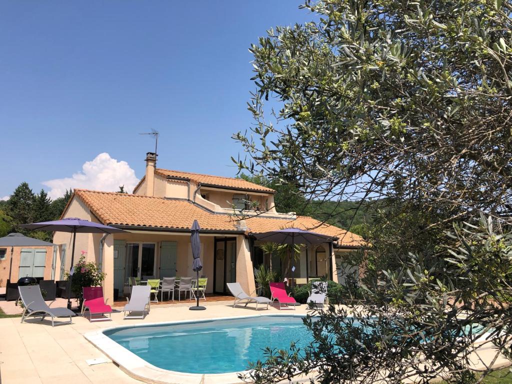 a villa with a swimming pool in front of a house at La Villa des 3 ifs in Vallon-Pont-dʼArc
