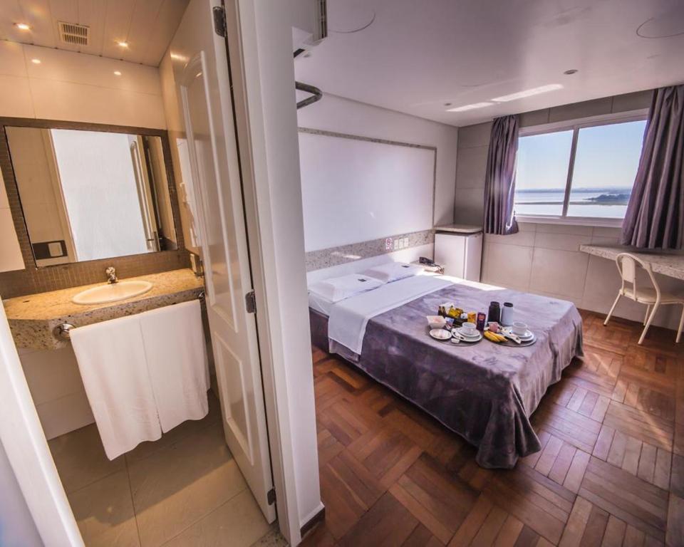 Pokój hotelowy z łóżkiem i umywalką w obiekcie Center Verdes Pássaros Loft w mieście Porto Alegre