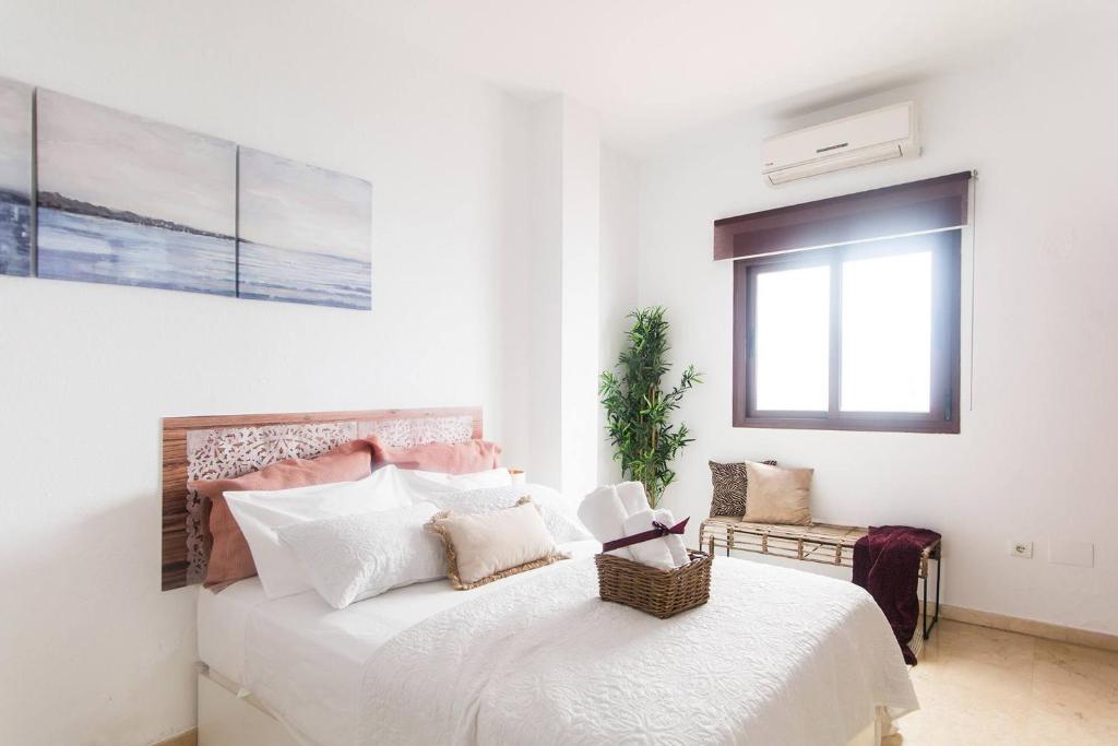 una camera da letto con un letto con lenzuola bianche e una finestra di Compas Suites a Málaga