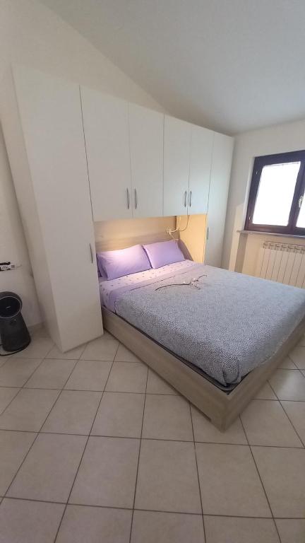 sypialnia z łóżkiem z fioletowymi poduszkami i oknem w obiekcie Monolocale Azzurra w mieście Magione