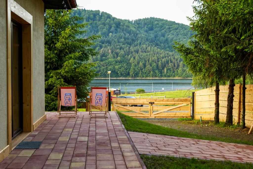 two chairs sitting on a walkway with a view of a lake at Willa Rybaczówka nad jeziorem Klimkówka in Klimkówka