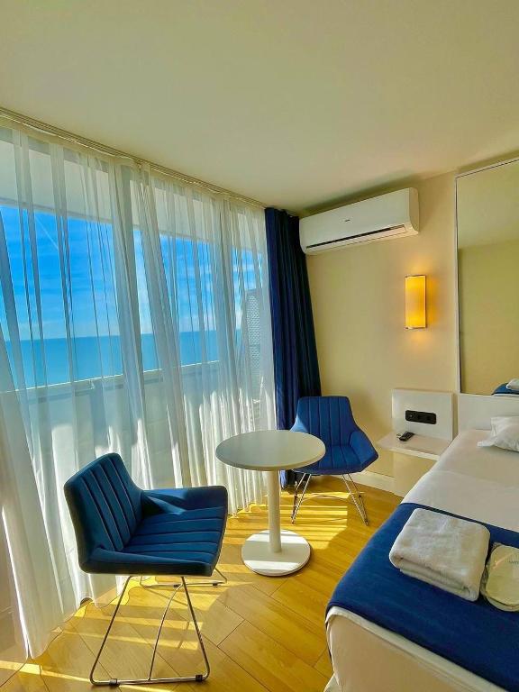 a hotel room with a bed and a table and chairs at Orbi city sea view apartments in Batumi