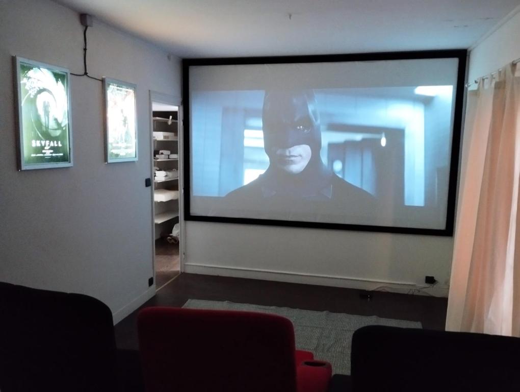 una gran pantalla de proyección en una habitación con una persona en ella en La cinéroom, en Bon-Encontre