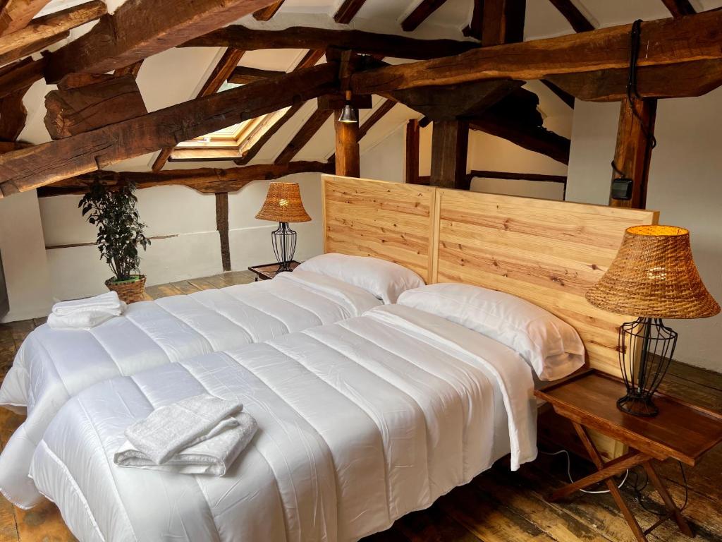 Casa Rural Basiver - Suite Basiver في Armaño: سرير أبيض كبير في غرفة ذات أسقف خشبية