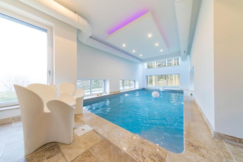 a swimming pool in a room with a large window at Home des bois in Ventron