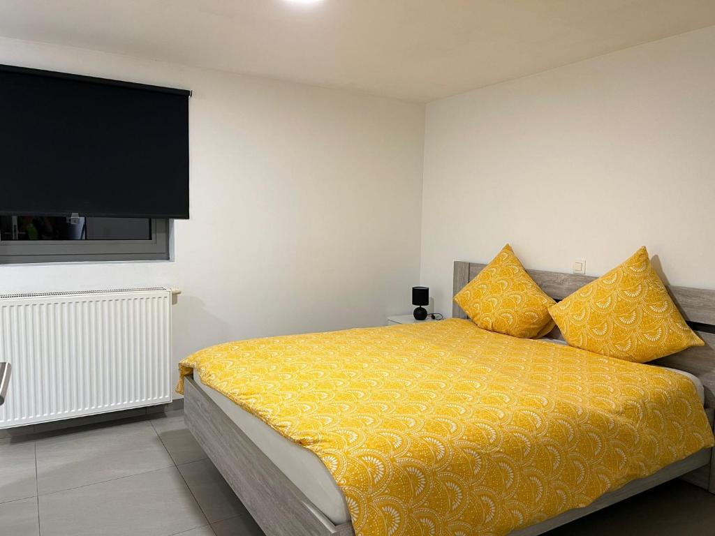 Alexa Residence - Appartement 1 في روسيلاري: غرفة نوم مع سرير مع أغطية صفراء وتلفزيون بشاشة مسطحة
