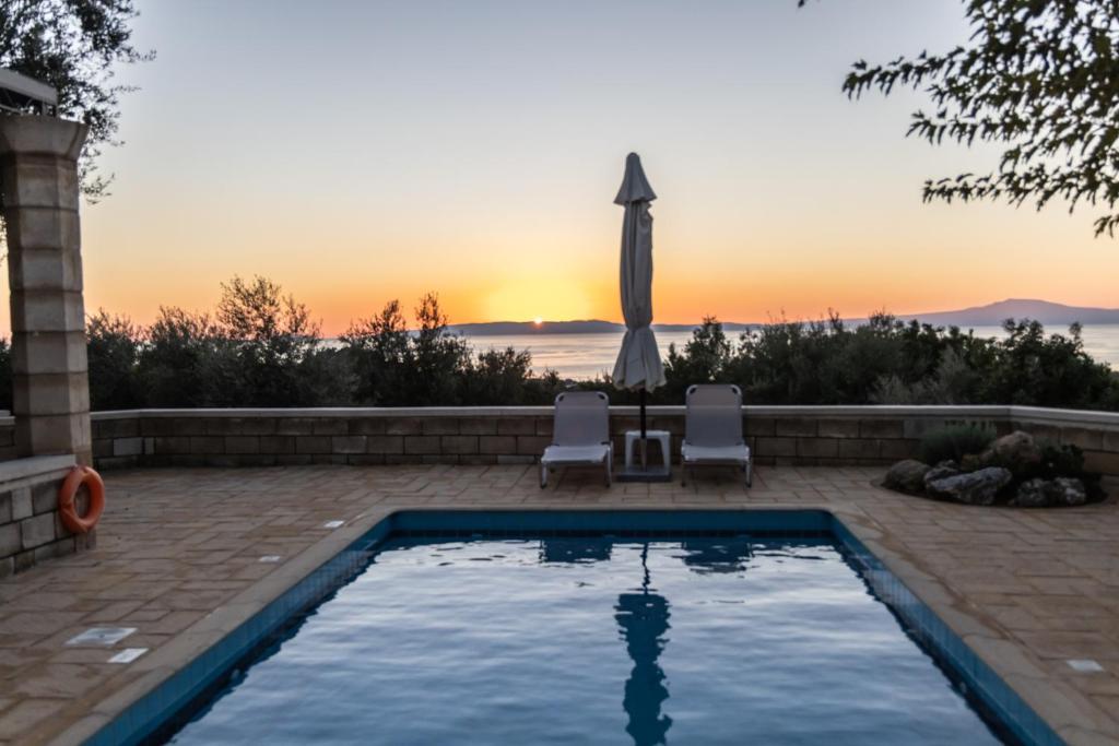 a swimming pool with a sunset in the background at Trochalo Villas 2 in Stoupa